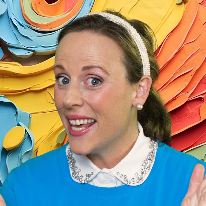 Birdie smiling in her bright blue sweater against a colourful backdrop